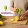 A person is using a wavy-edged knife to cut a potato on a wooden cutting board. There are already sliced potatoes on the board, and other vegetables are visible in the background. Produktbild-Vorschau