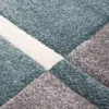 A close-up view of a textured rug with geometric patterns in blue, gray, and white. Voir les images du produit