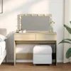 A vanity table with a mirror and lights, a stool, and some decorative items in a bedroom setting. Náhľad obrázku produktu