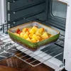 A square ceramic dish filled with chopped potatoes and tomatoes is placed on a metal rack inside an oven. Náhled obrázku produktu