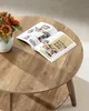 A close-up shot of a wooden coffee table with an open magazine and a small vase of flowers. Produktbild-Vorschau