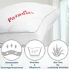 A close-up of a white pillow with the brand name 'Paradies' in red. Below the pillow are three circular icons with text, highlighting product features. Produktbild-Vorschau