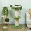 A cat is resting on a green cat tree with sisal scratching posts, next to a potted plant and a couch. Produktbild-Vorschau