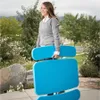 A woman is carrying a blue folding table outdoors. Podgląd zdjęcia produktu