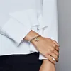 A close-up shot of a woman's wrist wearing a silver Pandora bracelet with a charm. Anteprima dell’immagine prodotto