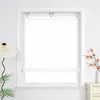 A white patterned roller blind is shown in a window frame, with a lamp and plant on the left and a vase with branches on the right. Produktbild-Vorschau