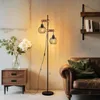 A living room scene featuring a floor lamp, a side table with flowers, and a sofa. Produktbild-Vorschau