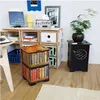 A collection of modular storage units and a decorative stool are arranged in a room, showcasing books and a plant. Podgląd zdjęcia produktu