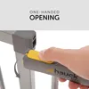A close-up of a hand operating a safety gate latch mechanism. Voir les images du produit