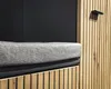 A close-up view of a shoe bench with a grey upholstered seat and wooden slatted sides. Produktbild-Vorschau