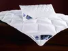 A white quilted duvet and pillow are laid out on a dark wooden surface. Produktbild-Vorschau