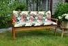 A wooden bench with a floral cushion sits on a green lawn in a garden setting. Produktbild-Vorschau