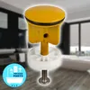 A close-up of a yellow drain stopper with a white base and a metal screw, set against a blurred background of a modern bathroom. Produktbild-Vorschau