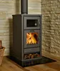 A modern, dark gray wood-burning stove with a glass door showing flames, set against a stone wall. Produktbild-Vorschau