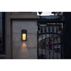 An outdoor wall light mounted on a stone wall next to a decorative metal gate. Anteprima dell’immagine prodotto
