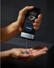 A hand holding a NIVEA MEN ACTIVE CLEAN shower gel bottle, dispensing the product into another hand. Podgląd zdjęcia produktu