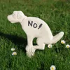 A white dog-shaped garden ornament with the word 'No!' written on its side, placed in a grassy area with daisies. Produktbild-Vorschau