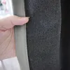 A hand is holding a gray curtain, showing the texture and stitching. Produktbild-Vorschau