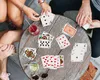 People playing cards around a wooden table with drinks. Produktbild-Vorschau