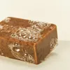 A bar of brown soap with bubbles on a white surface. Produktbild-Vorschau