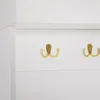A close-up view of two gold hooks on a white wall. Anteprima dell’immagine prodotto