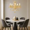 A gold chandelier hangs above a round dining table with four chairs. Anteprima dell’immagine prodotto