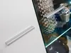A close-up of a modern furniture handle on a white surface, with a glass cabinet containing decorative items in the background. Produktbild-Vorschau