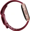 A close-up side view of a Fitbit Versa 4 fitness tracker with a raspberry red band and copper rose casing, isolated on a white background. Podgląd zdjęcia produktu