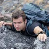A man is climbing a rocky surface while wearing a backpack and a smartwatch. Podgląd zdjęcia produktu