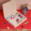 A sewing kit is displayed inside an open wooden box, with various spools of thread, needles, a pincushion, and scissors in a metal cup. Produktbild-Vorschau