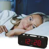 A woman in a bathrobe lies in bed, smiling, with a digital alarm clock in the foreground. Produktbild-Vorschau