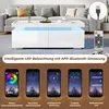 A modern white coffee table with integrated LED lighting, shown in a living room setting with a sofa and decorative items. Below the table, there are five smartphone screens displaying different app interfaces for controlling the LED lights. Voir les images du produit