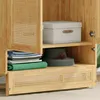 Close-up view of the interior of a wooden cabinet with a rattan door panel. Produktbild-Vorschau