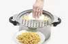 A hand is using a Spätzle maker to create noodles over a pot, with a plate of finished noodles in the foreground. Podgląd zdjęcia produktu
