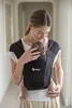 A woman is holding a baby in a black baby carrier. Produktbild-Vorschau