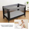 A baby crib and a person making a bed. Podgląd zdjęcia produktu