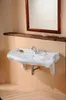 A white ceramic sink with a chrome faucet is mounted on a peach-colored wall. Anteprima dell’immagine prodotto