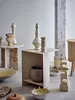 A collection of decorative ceramic and stone objects arranged on a floor and tables. Produktbild-Vorschau