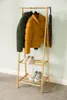 A wooden garment rack with two shelves holding jackets and shoes, against a light blue wall. Podgląd zdjęcia produktu
