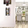 A wine rack mounted on a white wall, with a dining room and kitchen visible in the background. Produktbild-Vorschau