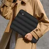 A person holding a black laptop sleeve. Produktbild-Vorschau