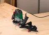 A router tool with a guide attachment is placed on a wooden workbench. Produktbild-Vorschau