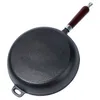 The underside of a cast iron frying pan with a wooden handle is shown against a white background. Produktbild-Vorschau