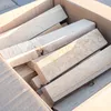 A close-up view of several pieces of light-colored wood stacked inside a cardboard box. Produktbild-Vorschau