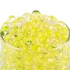 A close-up view of yellow and clear water beads in a glass container. Produktbild-Vorschau