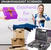 A woman is sitting with her legs crossed, holding a screwdriver, while a gift box is being handed to her. A toolbox is also visible in the foreground. Produktbild-Vorschau