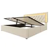 A beige upholstered bed frame with its storage compartment open, revealing the hydraulic lift mechanism and slatted base. The headboard has diamond tufting and integrated LED lighting. Náhľad obrázku produktu