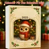 A festive image of an owl wearing a Santa hat and scarf, sitting in front of a decorated Christmas tree, with gifts in the background. The image is framed with festive holly and has the year '2025' prominently displayed. Produktbild-Vorschau