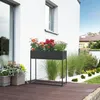 A modern planter with flowers on a wooden deck in front of a white house. Podgląd zdjęcia produktu