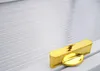 A close-up shot of a gold-colored leaf-shaped object and a gold-colored rectangular object on a textured white surface. Anteprima dell’immagine prodotto